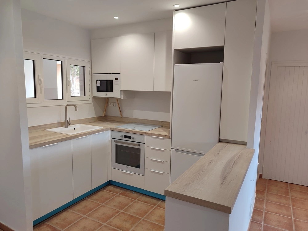 Diseño de cocinas a medida con muebles blancos, encimera de madera y distribución funcional